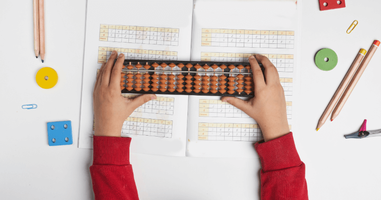 Dijete drži abakus položen na list papira s matematičkim zadacima